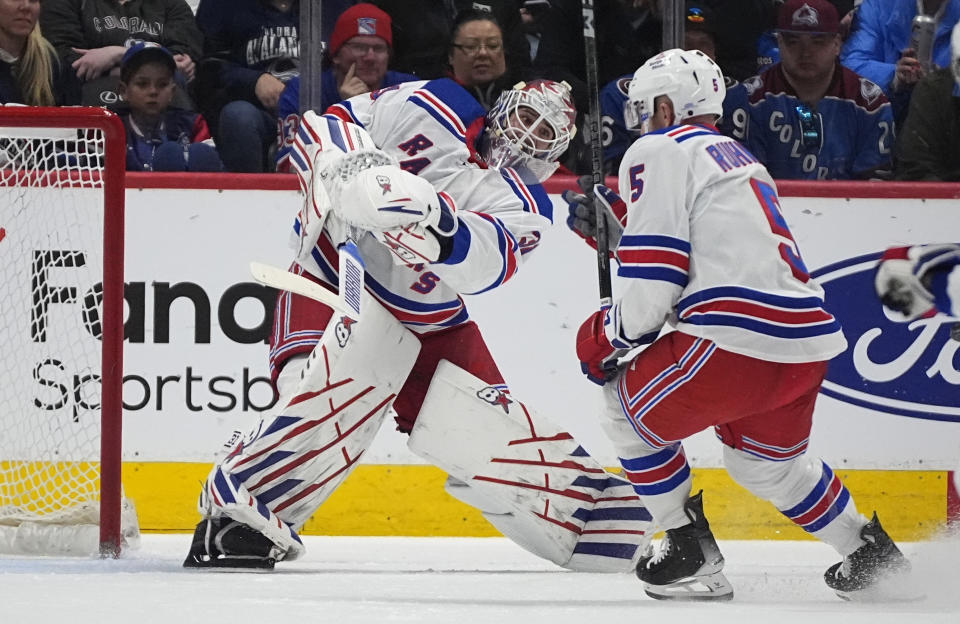 New York Rangers goaltender Igor Shesterkin, left, clears the puck past defenseman Chad Ruhwedel during the second period of the team's NHL hockey game against the Colorado Avalanche on Thursday, March 28, 2024, in Denver. (AP Photo/David Zalubowski)