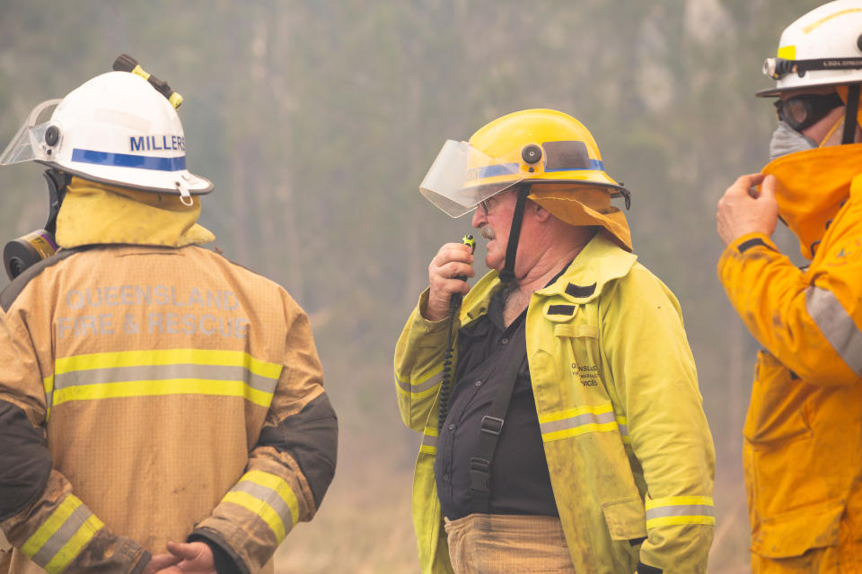 Three firefighters are seen near fires at Lake Cooroibah Road in Noosa.