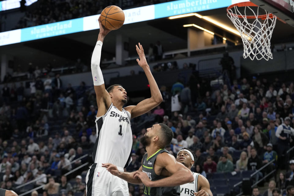 San Antonio Spurs center Victor Wembanyama (1) goes up for a shot as Minnesota Timberwolves center Rudy Gobert, bottom, defends during the second half of an NBA basketball game, Wednesday, Dec. 6, 2023, in Minneapolis. (AP Photo/Abbie Parr)