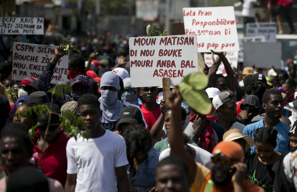 In this Feb. 12, 2020 photo, a protester holds a sign that reads in Creole "The people of Martissant are tired of dying from criminals' bullets," referring to one of the capital's most dangerous neighborhoods, during a march against violence in Port-au-Prince, Haiti. Two years after the departure of U.N. peacekeepers, young bandits with automatic weapons randomly halt cars on the main routes in and out of the capital. (AP Photo/Dieu Nalio Chery)