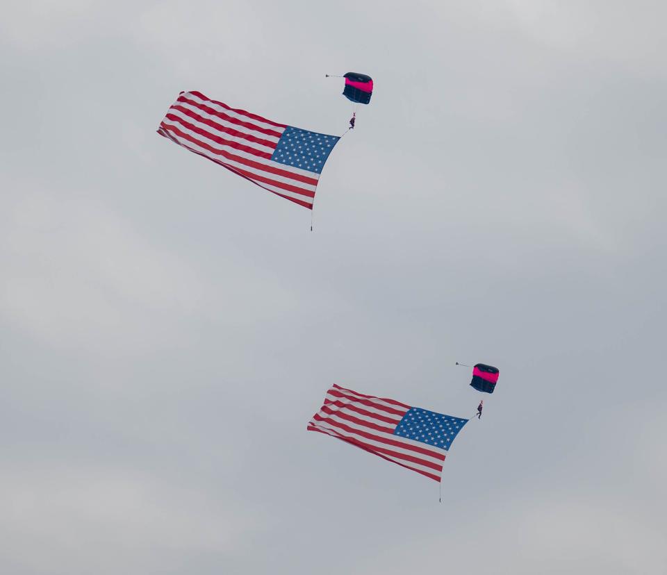 The Misty Blues All-Woman Skydiving Team with American flags perform at an air show and balloon festival.