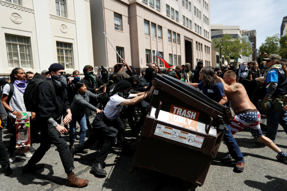 Demonstrators for (R) and against (L) U.S. President Donald Trump push a garbage container toward each other during a rally in Berkeley, California in Berkeley, California, U.S., April 15, 2017. REUTERS/Stephen Lam TPX IMAGES OF THE DAY