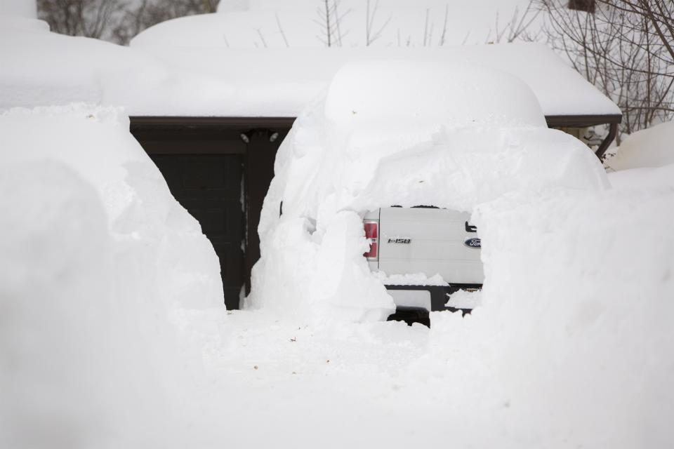 A snow-covered truck is parked in a driveway in the town of West Seneca near Buffalo, New York