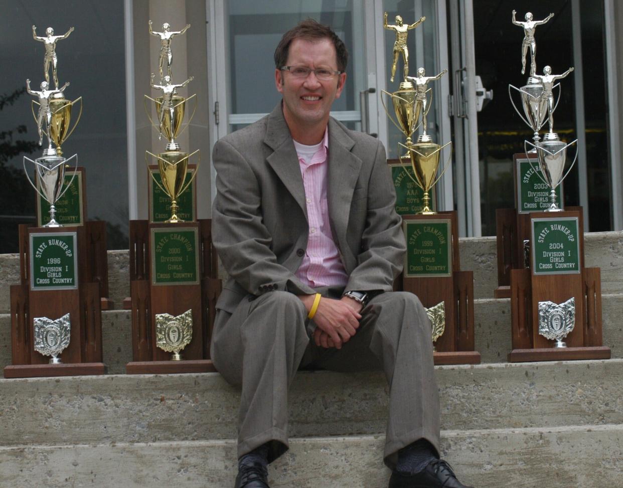 In a 2009 photo, Ron Russo sat among the eight Ohio High School Athletic Association trophies he had helped deliver to Colerain High School. He left Colerain to assume head coaching responsibilities at McAuley High School.