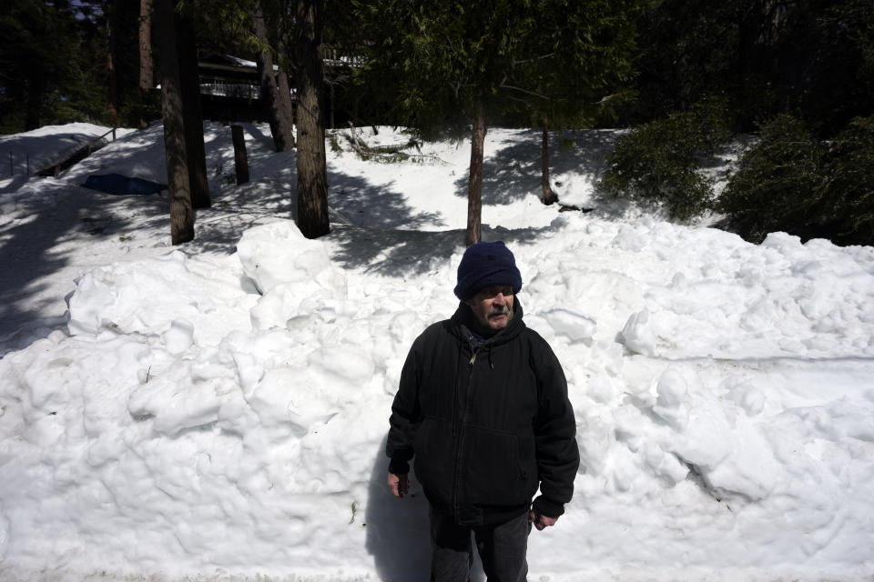 Resident Don Black stands in front of a mound of snow near his property after a series of storms, Wednesday, March 8, 2023, in Crestline, Calif. (AP Photo/Marcio Jose Sanchez)