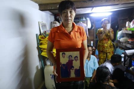 Than Dar, the wife of slain journalist Par Gyi, holds a family photograph showing herself, her husband and daughter posing with Aung San Suu Kyi at their home, in Yangon October 28, 2014. REUTERS/Soe Zeya Tun