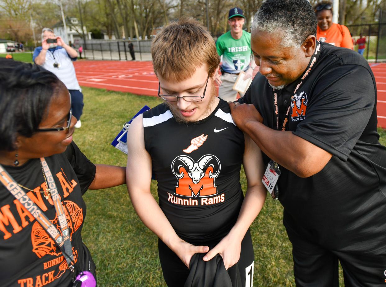 RON JOHNSON/JOURNAL STAR Special needs student Ethan Ewing gets a hug from Manual track coaches Harvey Burnett, right, and Karen Smith after his run in the boys 100 meter dash during Wednesday's City track and field meet.