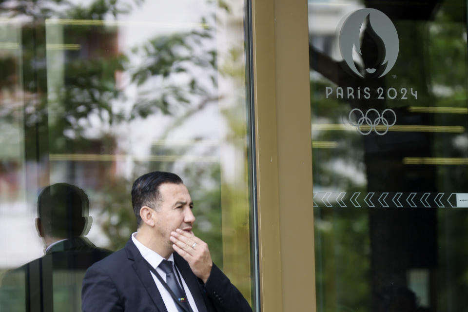 A door keeper reacts outside the headquarters of the Paris Olympic organizers, Tuesday, June 20, 2023 in Saint-Denis, outside Paris. French investigators searched the headquarters of Paris Olympic organizers on Tuesday in a probe into suspected corruption, according to the national financial prosecutor's office. (AP Photo/Thomas Padilla)