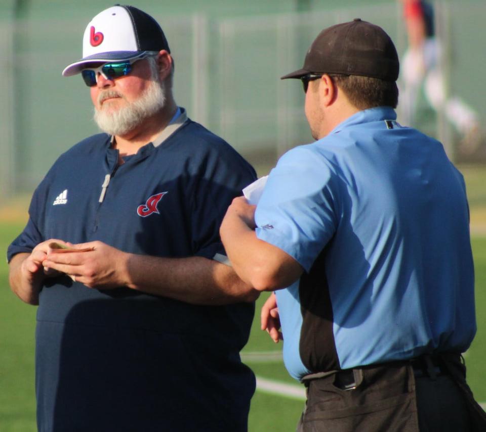 Bartlesville Doenges Ford Indians manager John Pannell, left, participates in the pre-game umpire conference during the Bartlesville Memorial Day Weekend baseball tourney.