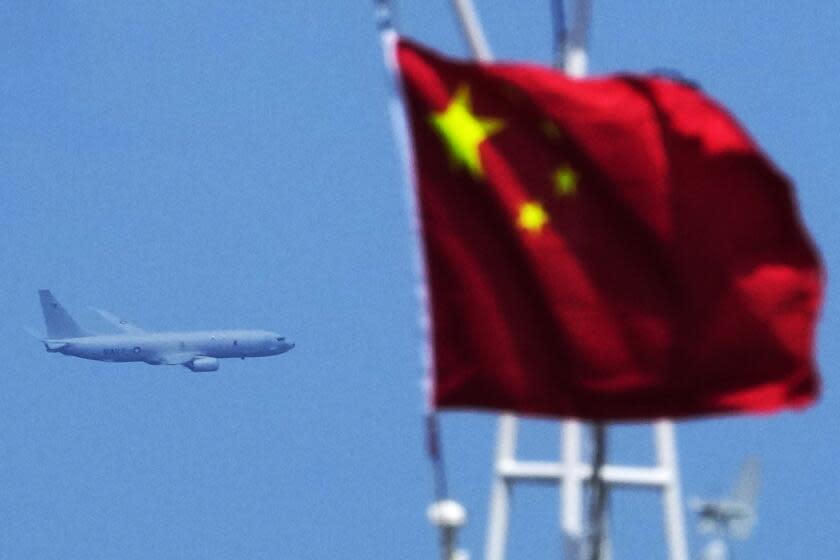 FILE - A U.S. Navy plane passes by a Chinese flag as it flies over the areas of Second Thomas Shoal, locally known as Ayungin Shoal, at the disputed South China Sea while Chinese coast guard ships tries to block Philippine coast guard and supply ships during a rotation and resupply mission on Aug. 22, 2023. (AP Photo/Aaron Favila, File)