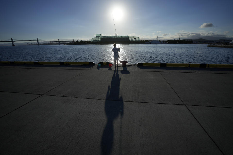 An angler fishes at Onahama Port in Iwaki, northeastern Japan, 68 kilometers (42 miles) from the Fukushima Daiichi nuclear power plant, damaged by a massive March 11, 2011, earthquake and tsunami, on Friday, Aug. 25, 2023. Fish auction prices at a port south of the Fukushima Daiichi nuclear power plant Friday somehow dipped amid uncertainty about how consumers may respond a day after release to sea of treated and diluted radioactive wastewater began despite protests at home and in neighboring countries. (AP Photo/Eugene Hoshiko)