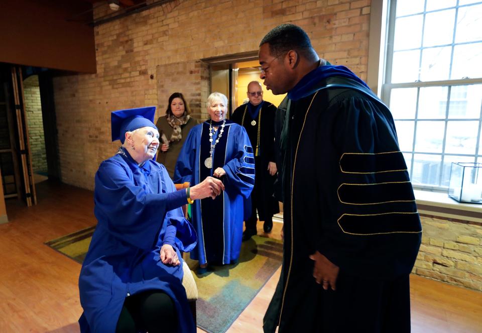 Rosemary Lloyd, 88, of Appleton chats with former Green Bay Packer George Koonce Jr., a senior vice president with Marian University, as she celebrates earning her bachelor's degree on Nov. 9 in Appleton. Koonce presented Lloyd with a Packers bracelet and a signed photograph of himself.