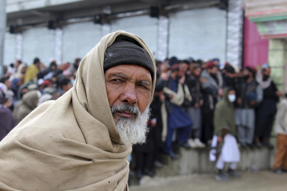 Afghans wait to receive food rations organized by the World Food Program (WFP) in Pul-e-Alam, the capital of Logar province. eastern of Afghanistan, Tuesday, Jan. 18, 2022. The Taliban's sweep to power in Afghanistan in August drove billions of dollars in international assistance out of the country and sent an already dirt-poor poor nation, ravaged by war, drought and floods, spiralling toward a humanitarian catastrophe. (AP Photo/Zubair Abassi)