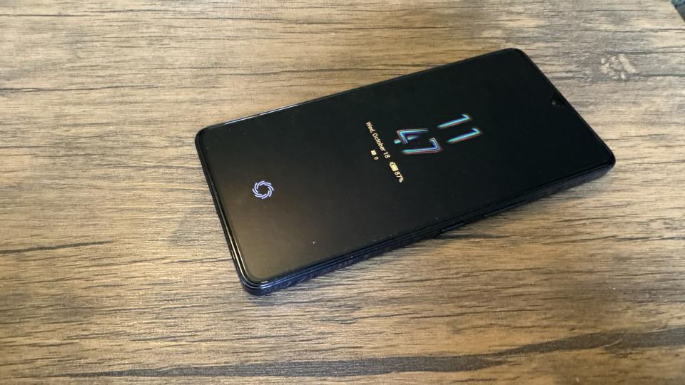 A Cyber Black Infinix GT 10 Pro camera phone on a brown wooden table