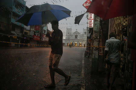 A man crosses a street during heavy rain near the security cordon surrounding St. Anthony's Shrine, days after a string of suicide bomb attacks on churches and luxury hotels across the island on Easter Sunday, in Colombo, Sri Lanka April 25, 2019. REUTERS/Thomas Peter