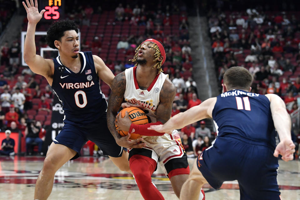 Louisville guard El Ellis (3) is fouled as he tries to split the defense of Virginia guards Kihei Clark (0) and Isaac McKneely (11) during the second half of an NCAA college basketball game in Louisville, Ky., Wednesday, Feb. 15, 2023. Virginia won 61-58. (AP Photo/Timothy D. Easley)