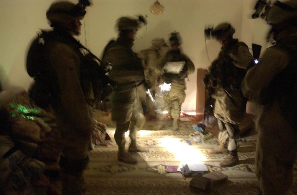 FILE - In this Wednesday, Jan. 14, 2004 file photo, soldiers with the 82nd Airborne Division spread out documents and other objects on the floor while looking for evidence during a raid on an Iraqi house near Fallujah, Iraq. The owner of the house is suspected of being responsible for attacks on coalition forces. In 2014, the city's fall to al-Qaida-linked forces has touched a nerve for the service members who fought and bled there. (AP Photo/Julie Jacobson)