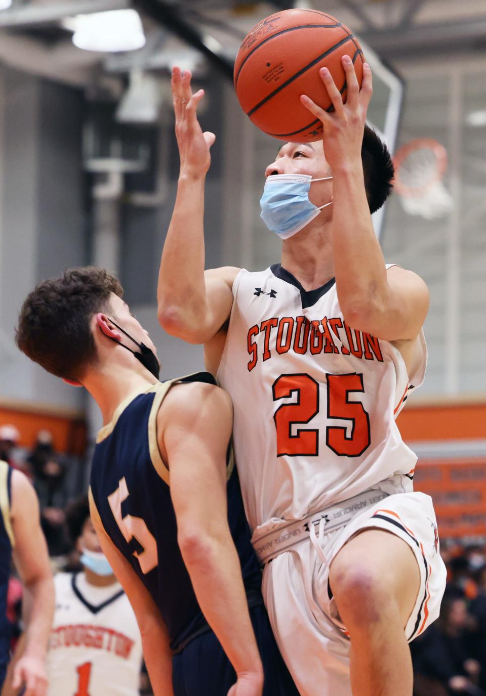 Stoughton's Jonah Ly scores a basket on Foxboro defender Ryan LeClair during a game on Wednesday, Feb. 16, 2022.  