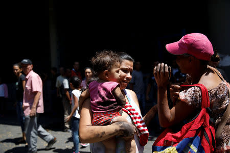 A woman carries her baby after they evacuated a metro station during a blackout in Caracas, Venezuela March 25, 2019. REUTERS/Carlos Garcia Rawlins