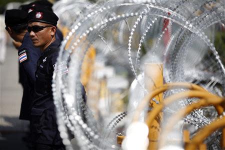 Policemen stand in front of razor wire as anti-government protesters arrive to the Defense Ministry in central Bangkok November 28, 2013. REUTERS/Damir Sagolj