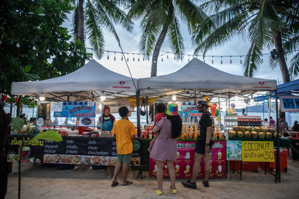 A family buys food from a stall at a market in Patong, Phuket, Thailand, on Saturday, December 19, 2020. Source: Getty