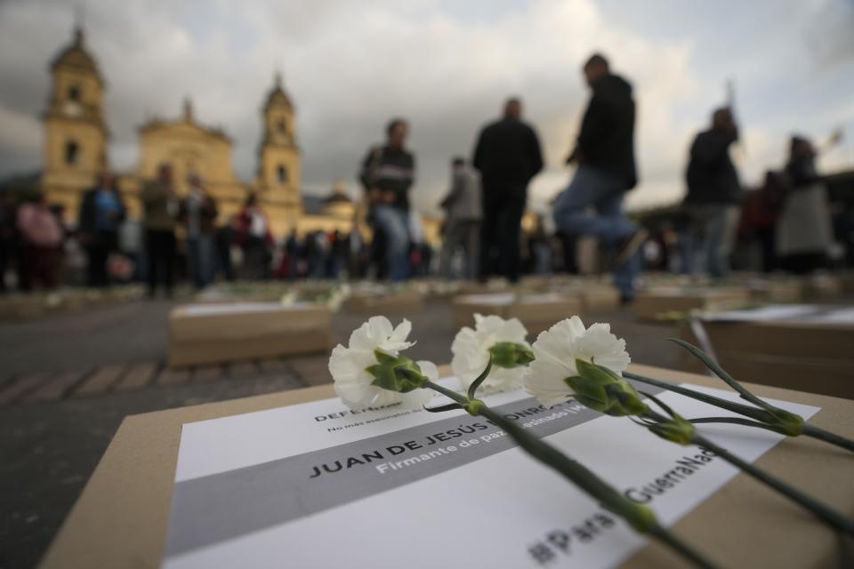 Flowers lie on boxes representing symbolic coffins during an event remember former guerrillas and social leaders who have been killed since the 2016 signing of a peace agreement between rebels of the Revolutionary Armed Forces of Colombia, FARC, and the government, in Bogota, Colombia, Tuesday, Feb. 20, 2024. (AP Photo/Fernando Vergara)