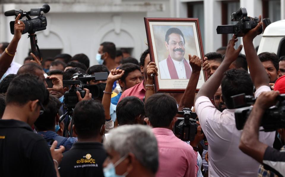 Pro-government supporters hold Prime Minister Mahinda Rajapaksa's portrait while protesting on Monday - Buddhika Weerasinghe/Getty Images