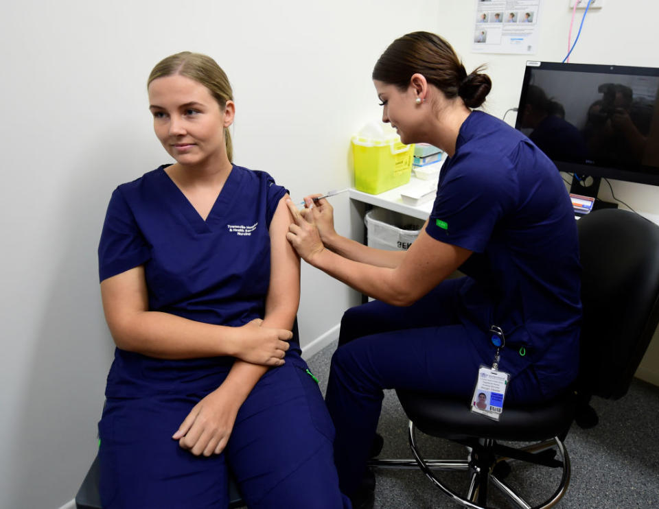 A nurse in scrubs receives a Pfizer vaccine at a Townsville centre.