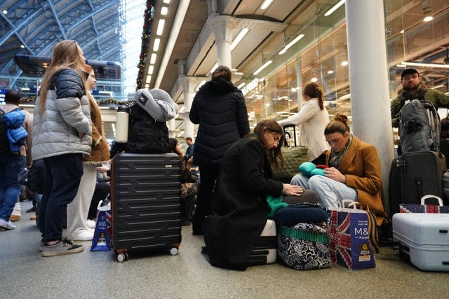 Passengers sit on the floor of the concourse at St Pancras International