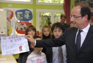 French President Francois Hollande (right) holds a drawing reading: "The change is now! Thank you" at a school in Dieudonne, north of Paris, this week. France votes in the opening round of a parliamentary election on Sunday with ollande's Socialists and their left-wing allies expected to emerge with a clear majority