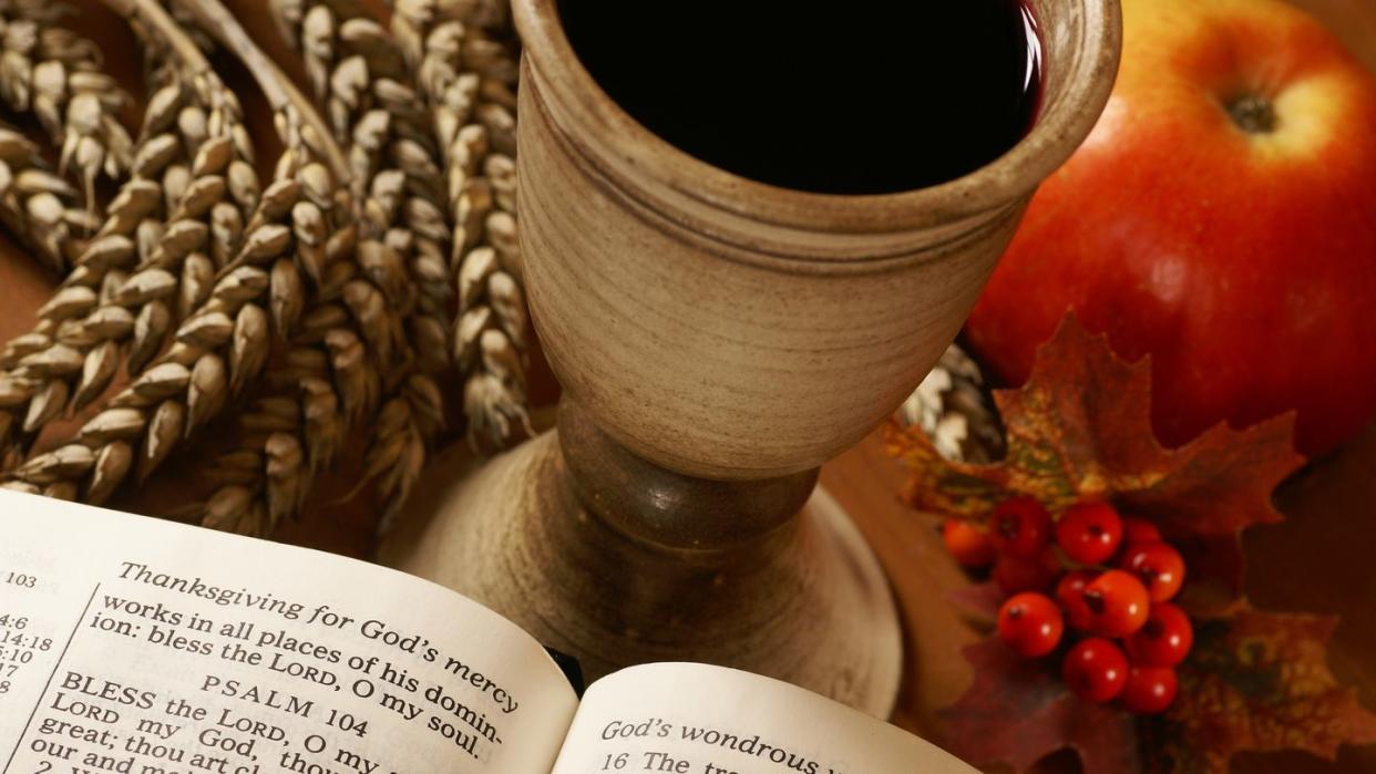 open bible, chalice with wine, ear and apple