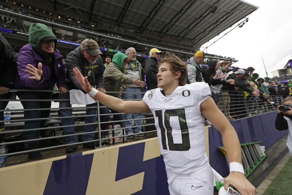 Justin Herbert, in Ducks uniform, gives a fan a high-five.