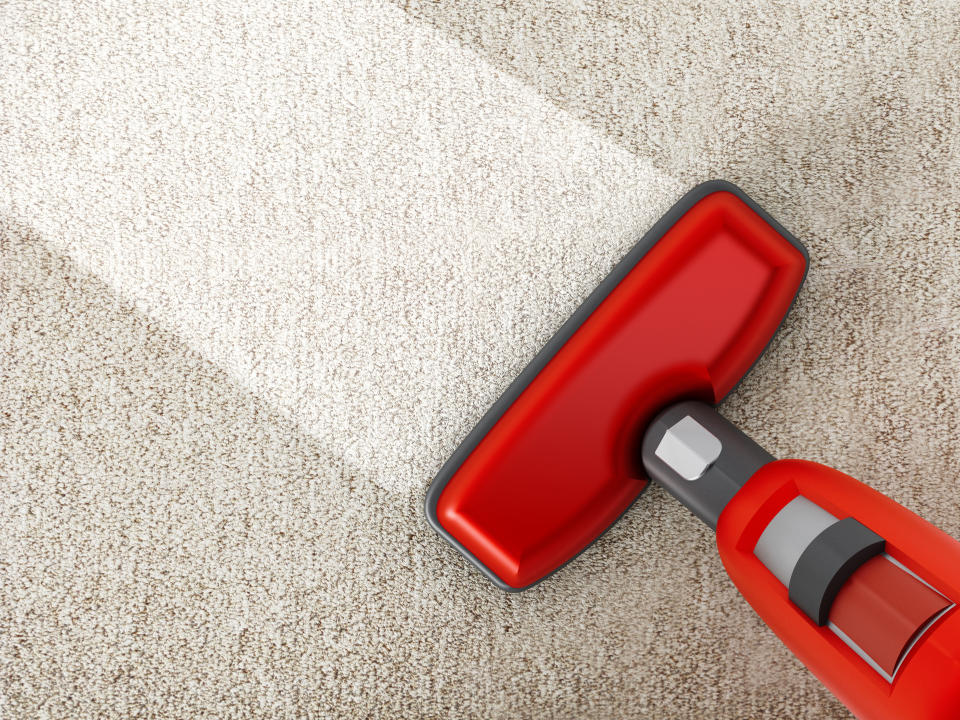 Red vacuum cleaner cleaning a carpet.