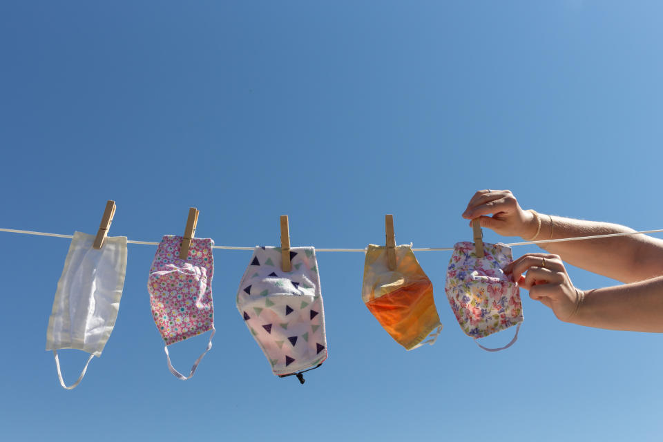 Woman hands stretching reusable cloth face masks on a clothesline