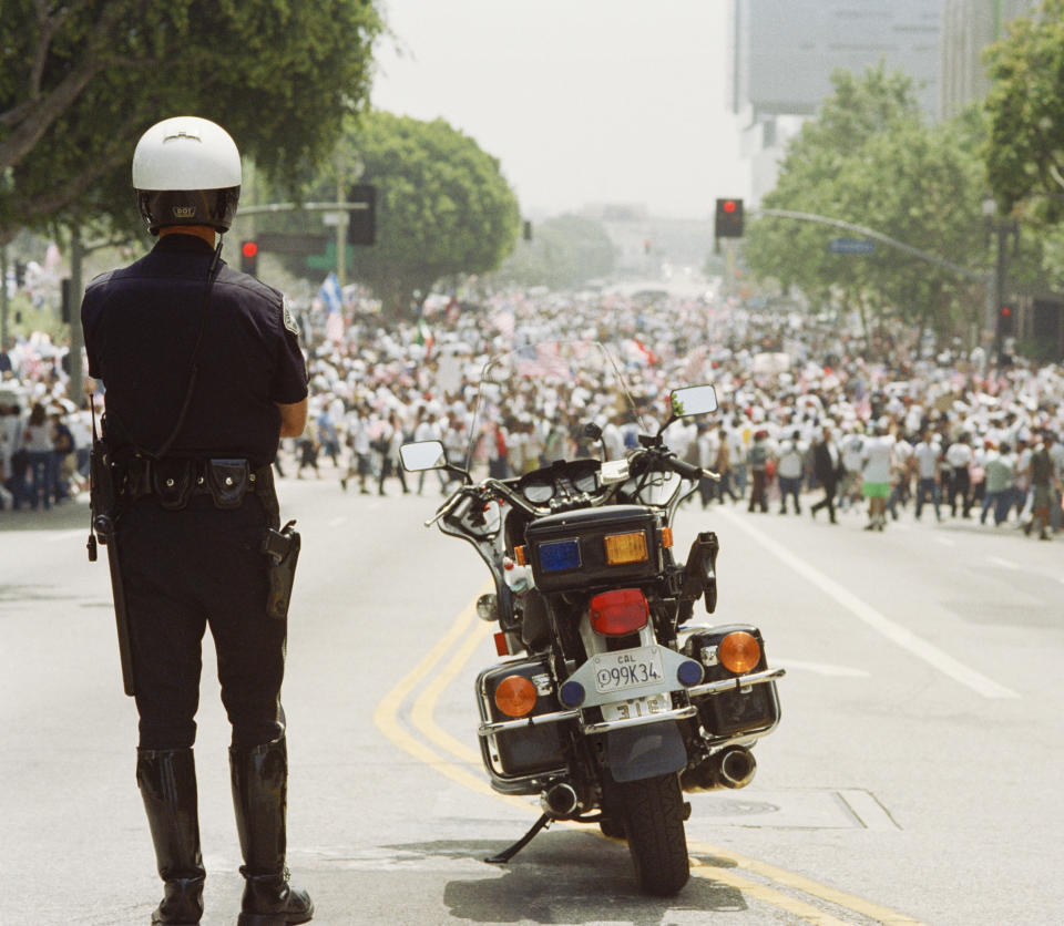 A policeman is standing in front of a protest