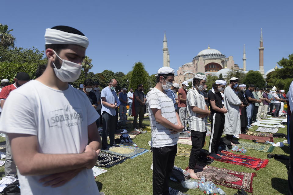 Muslims pray during Friday prayers at the historic Sultanahmet district of Istanbul, near the Byzantine-era Hagia Sophia, background, Friday, July 24, 2020. Thousands of Muslim faithful surrounded Istanbul's landmark monument Friday to take part in the first prayers in 86 years at the structure that was once Christendom's most significant cathedral and the "jewel" of the Byzantine Empire then a mosque and museum before its re-conversion into a Muslim place of worship. The conversion of the edifice, has led to an international outcry. (AP Photo/Yasin Akgul)