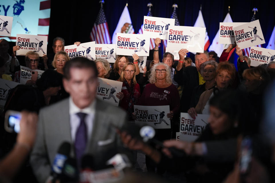 Republican U.S. Senate candidate Steve Garvey, front left, talks to reporters in front of supporters, Tuesday, March 5, 2024, in Palm Desert, Calif. (AP Photo/Gregory Bull)