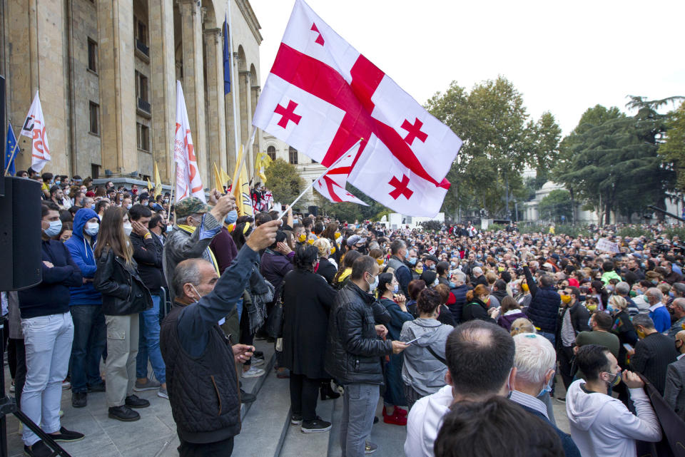 Supporters of the ex-President Mikhail Saakashvili's United National Movement, most of them wearing face masks to help curb the spread of the coronavirus, wave Georgian national flags during rally to protest the election results rally in front of the parliament's building in Tbilisi, Georgia, Sunday, Nov. 1, 2020. Preliminary election results show that Georgia's ruling party won the country's highly contested parliamentary election, but the opposition have refused to recognize Sunday's results. (AP Photo/Shakh Aivazov)