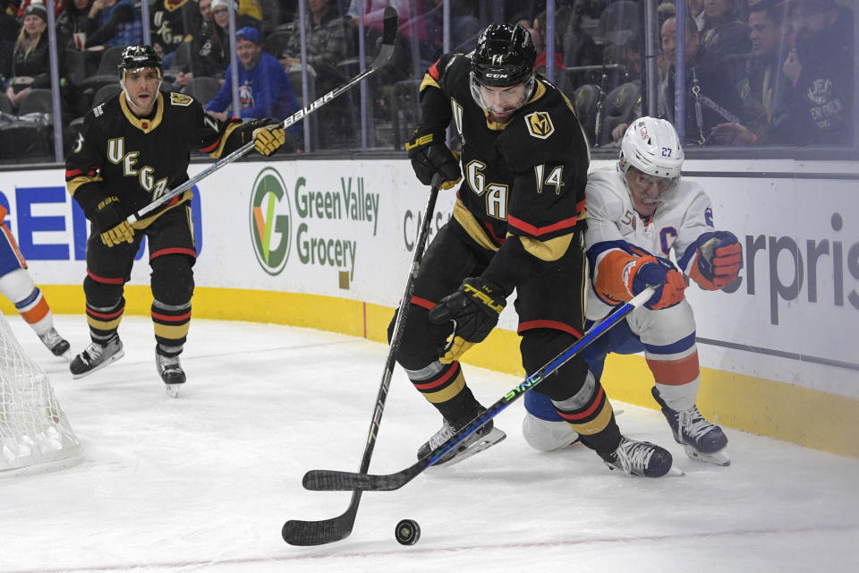 Vegas Golden Knights defenseman Nicolas Hague (14) gets the puck from New York Islanders left wing Anders Lee (27) during the third period of an NHL hockey game Saturday, Dec. 17, 2022, in Las Vegas. The Islanders defeated the Golden Knights 5-2. (AP Photo/Sam Morris)