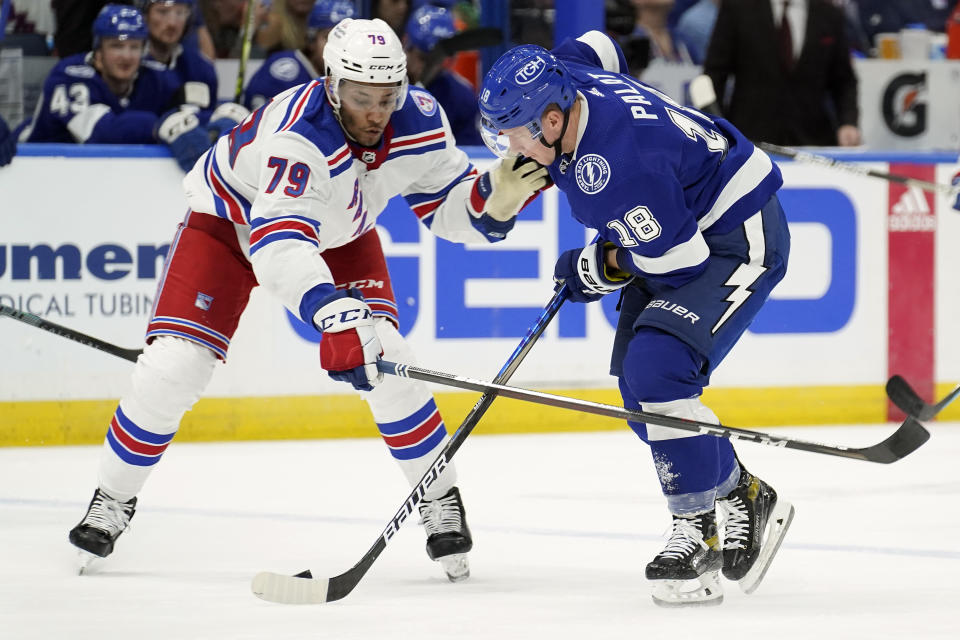 New York Rangers defenseman K'Andre Miller (79) knocks the puck away from Tampa Bay Lightning left wing Ondrej Palat (18) during the second period of an NHL hockey game Friday, Dec. 31, 2021, in Tampa, Fla. (AP Photo/Chris O'Meara)