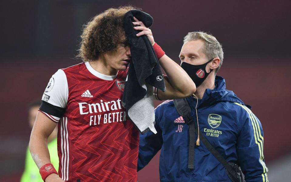 David Luiz of Arsenal receives treatment from Physio Jordan Reece for a head injury during the Premier League match between Arsenal and Wolverhampton Wanderers at Emirates Stadium on November 29, 2020 in London, England. Sporting stadiums around the UK remain under strict restrictions due to the Coronavirus Pandemic as Government social distancing laws prohibit fans inside venues resulting in games being played behind closed doors - Arsenal FC /David Price 