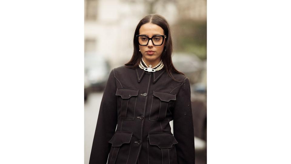 A guest wears white tights, black skirt and a jacket, black bag and green, yellow and black platform shoes outside Vivienne Westwood during the Womenswear Fall/Winter 2024/2025 as part of  Paris Fashion Week on March 02, 2024 in Paris, France