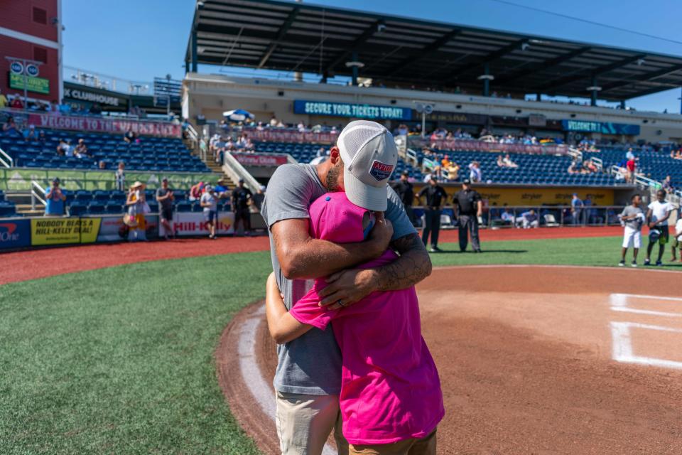 An 11-year-old boy, Carson, hugs his adoptive father after throwing out a first pitch on Father's Day with a ball that signified an adoption had become official.