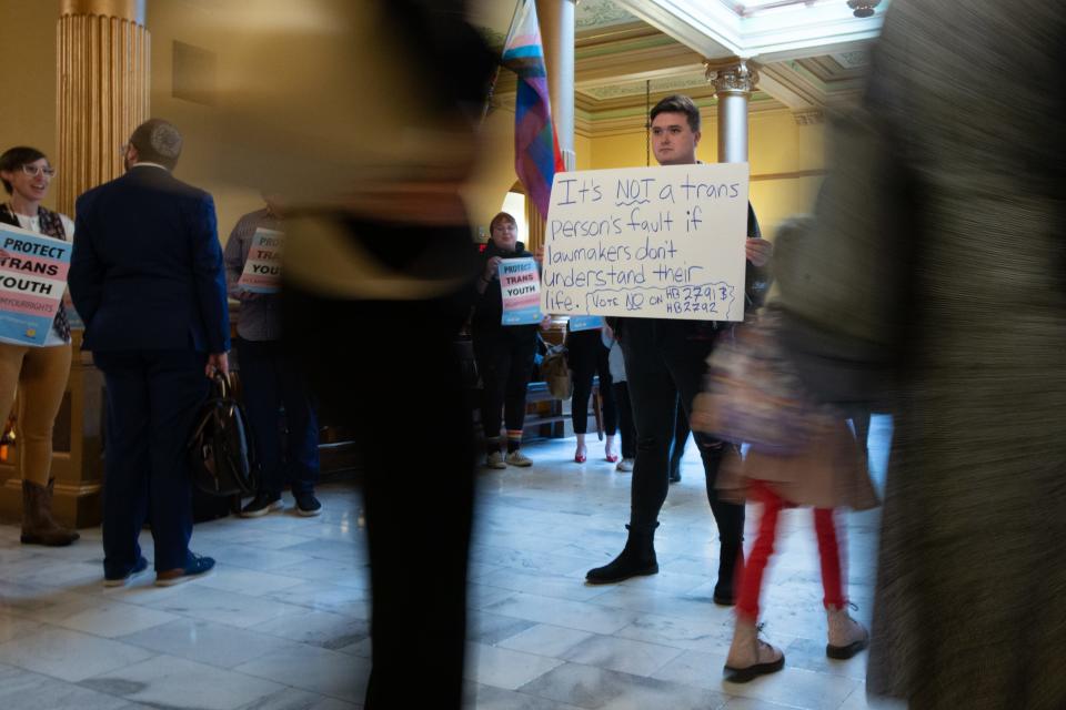 Jae Moyer, an Overland Park resident, holds a sign in opposition of HB 2791 and HB 2792 on gender-affirming care after a committee hearing Thursday at the Kansas Statehouse.