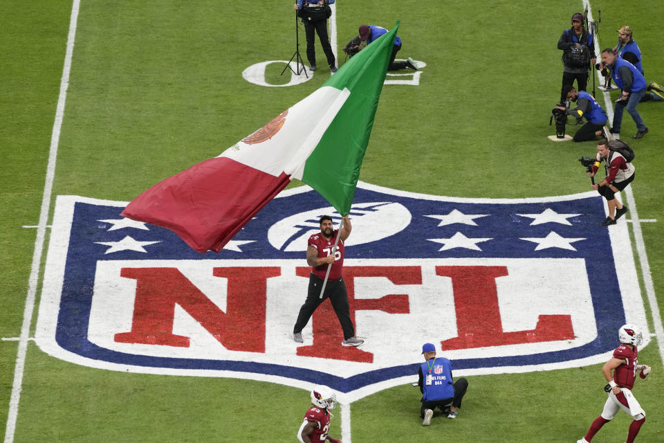 Arizona Cardinals offensive lineman Will Hernandez waves the flag of Mexico before an NFL football game against the San Francisco 49ers, Monday, Nov. 21, 2022, in Mexico City. (AP Photo/Eduardo Verdugo)