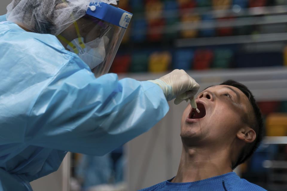 Swab sample is collected from a man at a makeshift testing site in the Queen Elizabeth Stadium in Hong Kong Tuesday, Sept.1, 2020. Hong Kong began a voluntary mass-testing program for coronavirus Tuesday as part of a strategy to break the chain of transmission in the city's third outbreak of the disease. (Anthony Kwan /Pool Photo via AP)