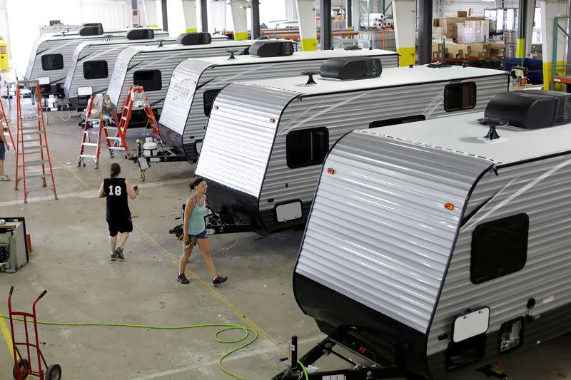 FILE PHOTO: Workers walk around a single axel towable Pioneer traditional recreational vehicles in Elkhart