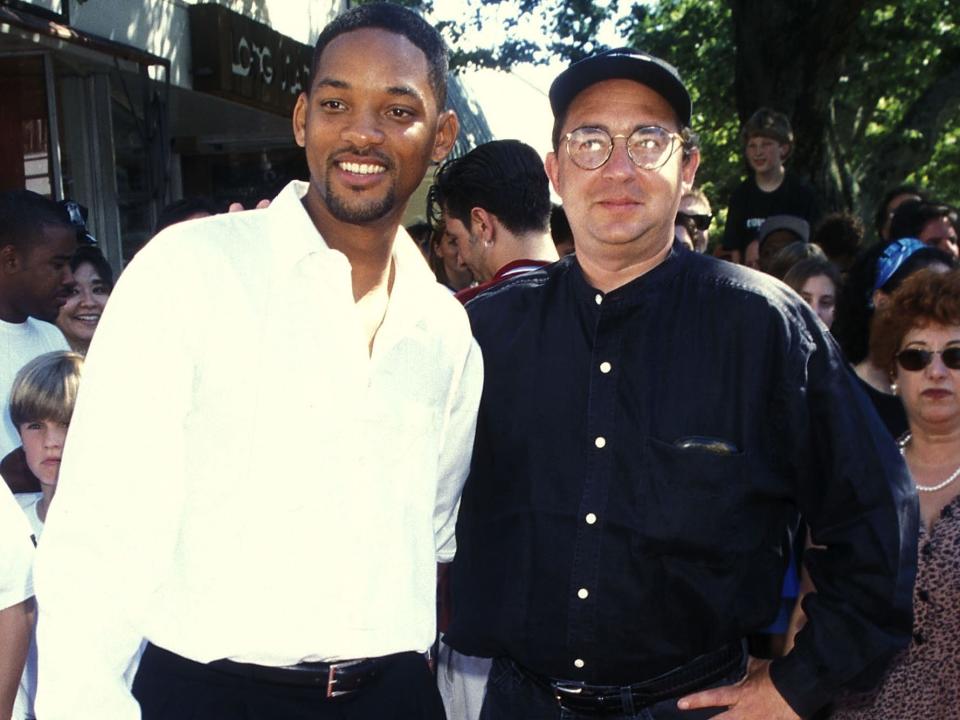 Will Smith in a white shirt standing next to Barry Sonnenfeld in a hat and dark shirt