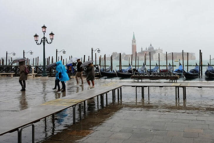 Varias personas pasan por la Plaza de San Marcos durante un evento excepcional de marea alta frenada por el sistema de barreras Mose en Venecia, Italia.