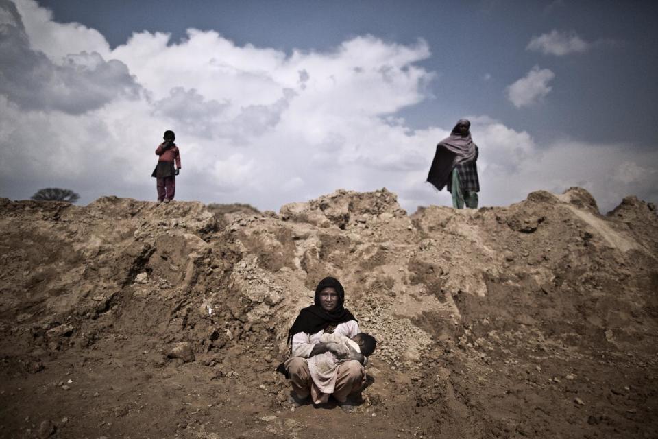 In this Sunday, March 2, 2014, photo, Ghaziya Iqbal, 35, a Pakistani brick factory worker, breast-feeds her child Farman, 9 months old, at the site of her work on the outskirts of Islamabad, Pakistan. Ghaziya and her husband are in debt to their employer the amount of 250,000 rupees (approximately $2500). (AP Photo/Muhammed Muheisen)